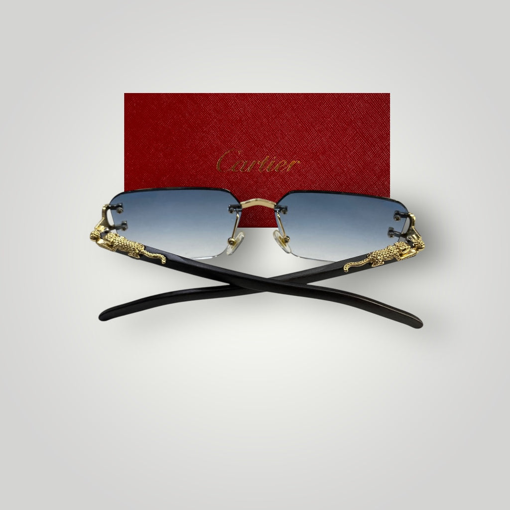 Luxury Cartier eyewear laid flat showing gradient blue lenses and intricate metal craftsmanship on rimless frame