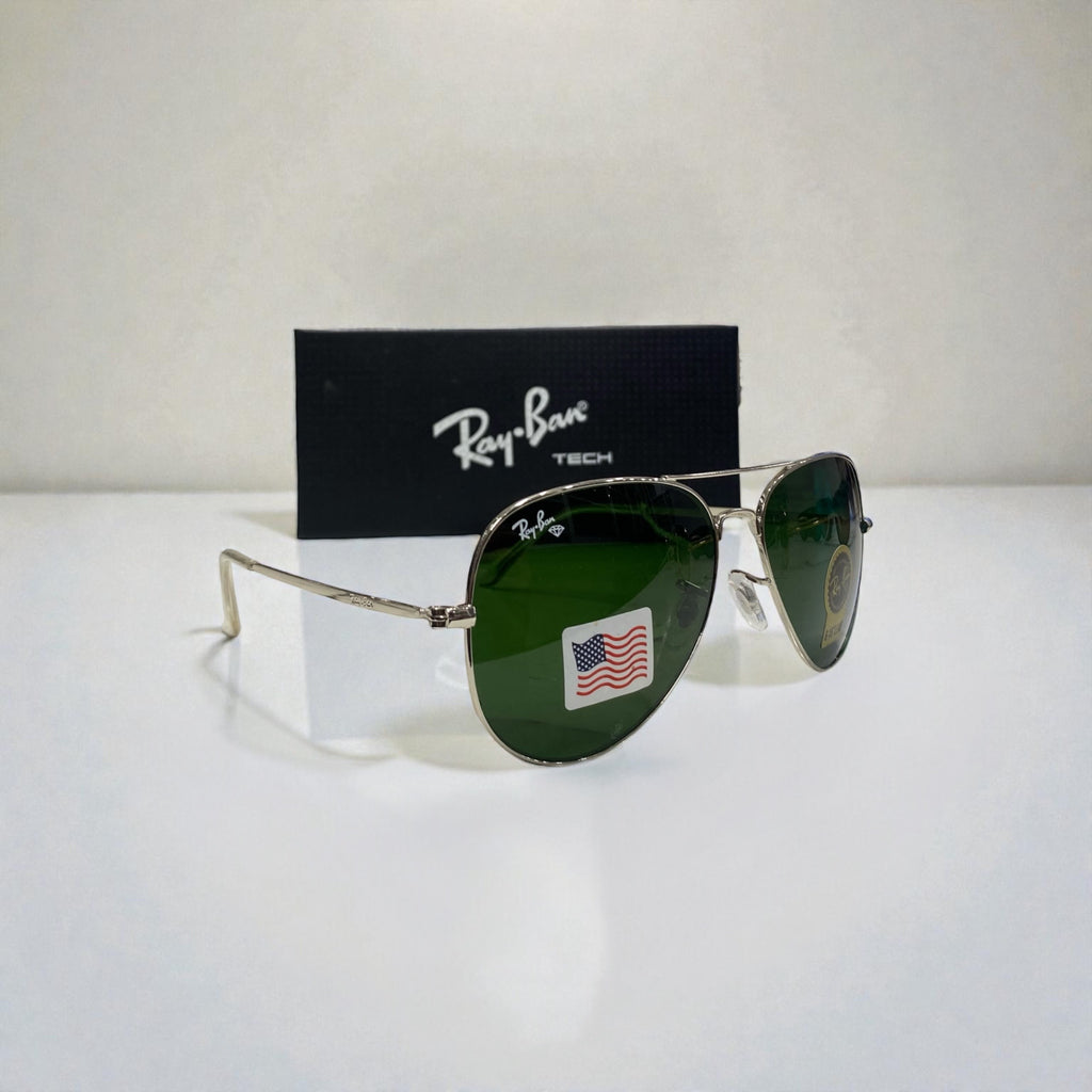 Ray-Ban Aviator sunglasses with silver frame and green lenses angled sideways on white surface with black Ray-Ban Tech branded box behind