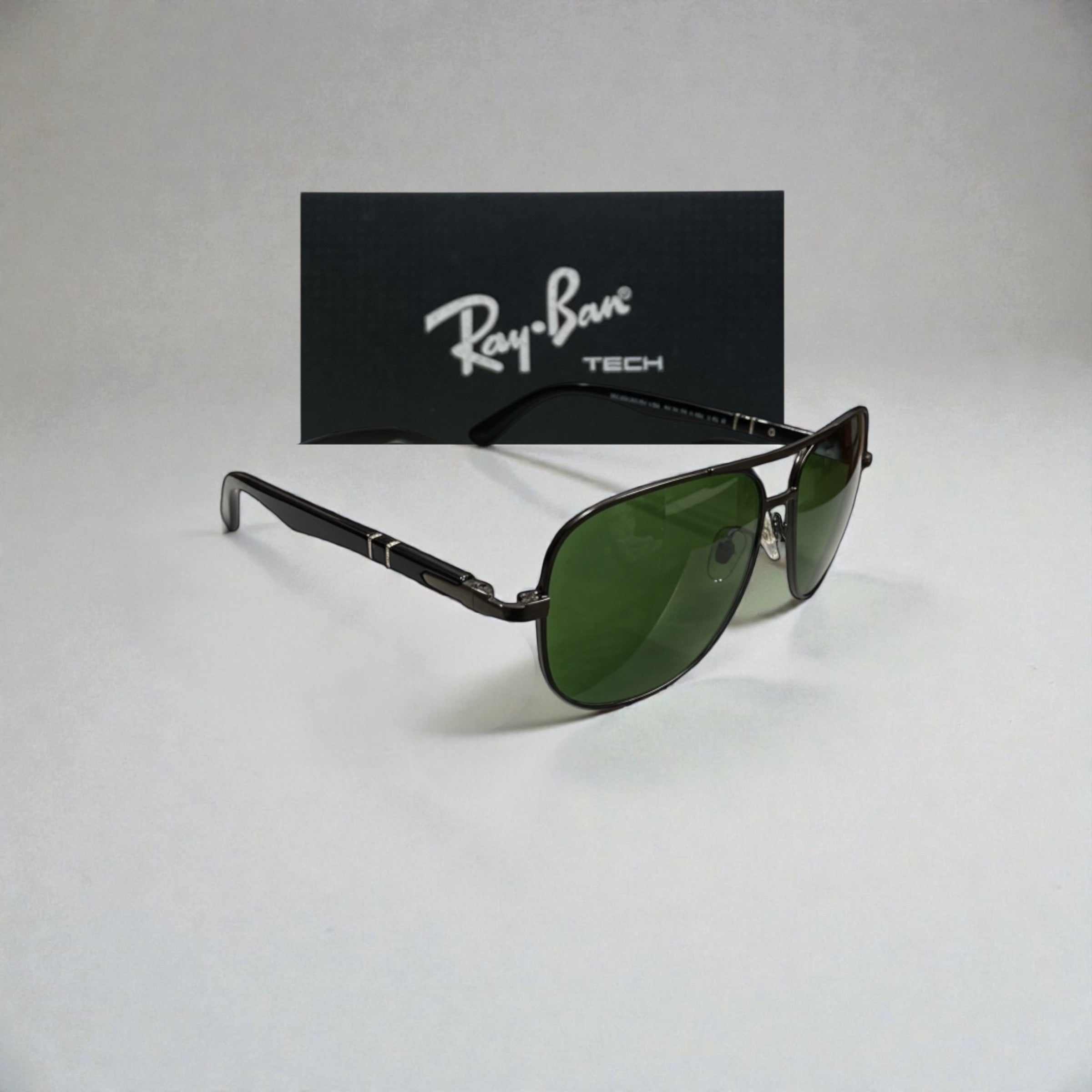 Side angle view of black metal Ray-Ban Tech aviator sunglasses with green lenses and Ray-Ban logo box in the background