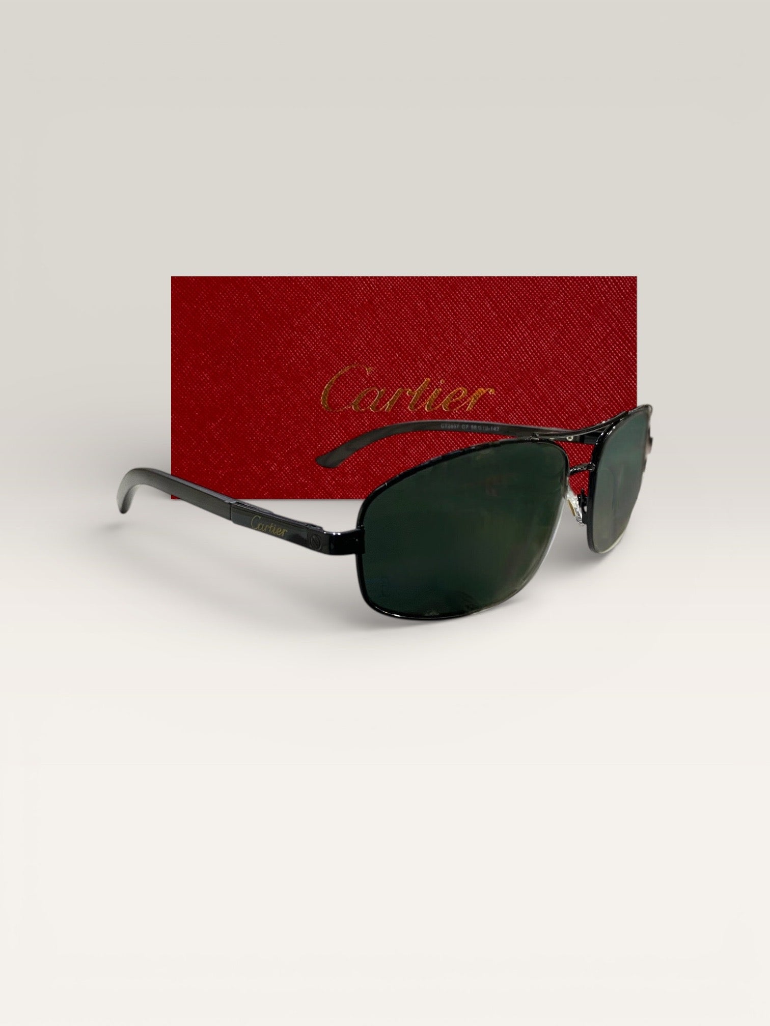 Side view of Cartier black metal frame sunglasses with green lenses in front of a red Cartier case