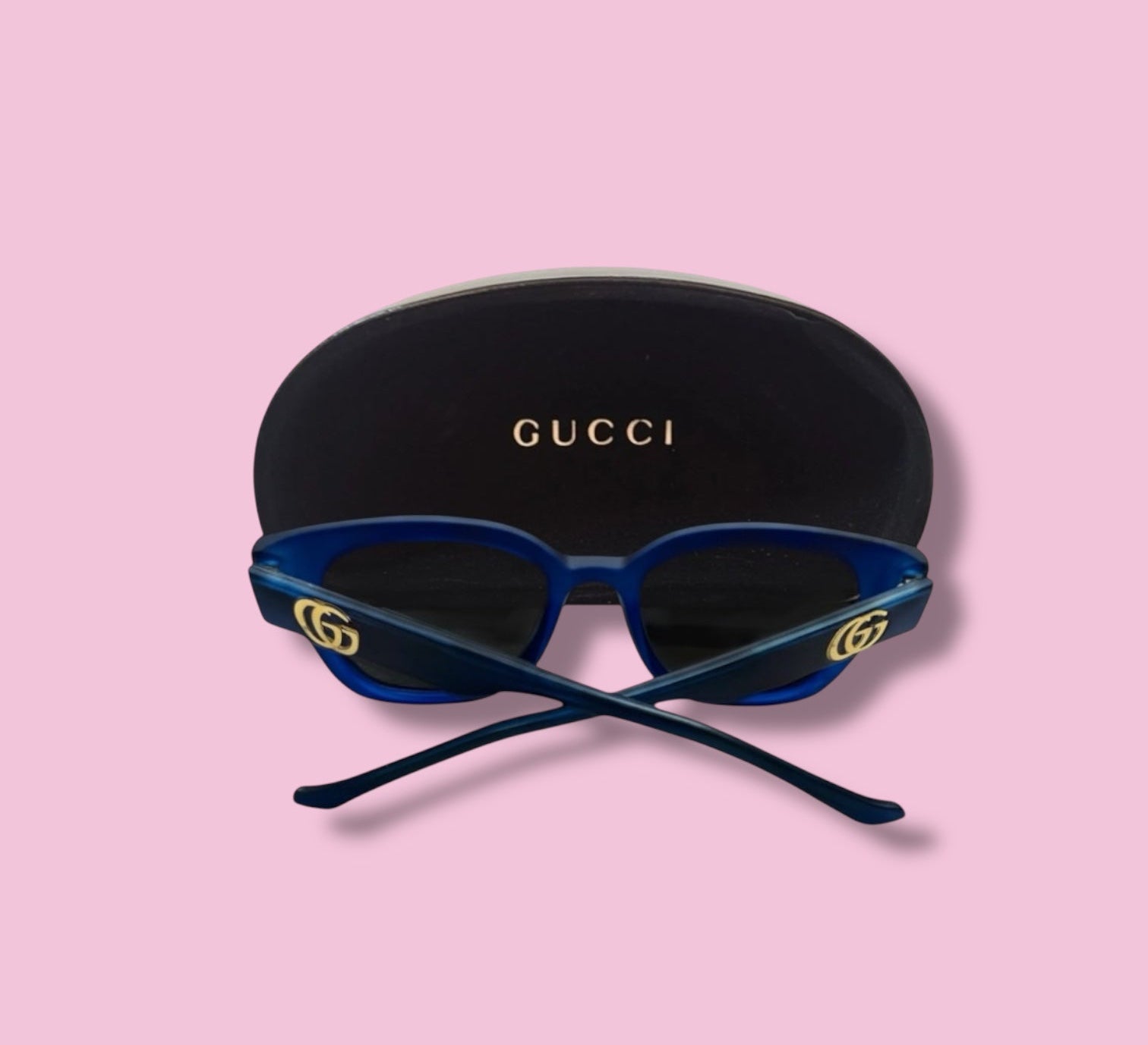 Back view of Beenai Original 3005 men's blue acetate sunglasses showing crossed temples and black Gucci case on pink background